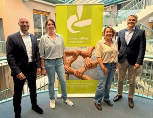 Links: neuer Vorstandsvorsitzender Heiko Nothacker und neue Leiterin der Geschäftsstelle Arite Tretter, rechts: bisherige Geschäftsstellenleitung Miriam Lämmle-Gorbach und bisheriger Vorstandsvorsitzender Jürgen Kiesl vor dem Plakat der Bürgerstiftung